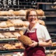 Fröhliche Mitarbeiterin einer Bäckerei mit Brot in der Hand