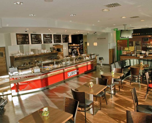 Ansicht leicht von oben der Gastronomie von CurryQ und Horsthemke mit verschiedenen Sitzgelegenheiten und zwei Theken