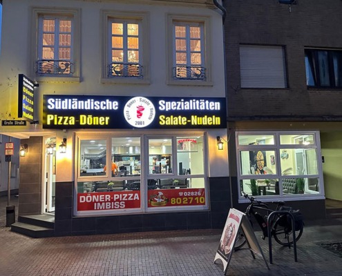 Außenansicht Südländische Spezialitäten Kranenburg in der Dunkelheit mit beleuchtetem Reklameschild