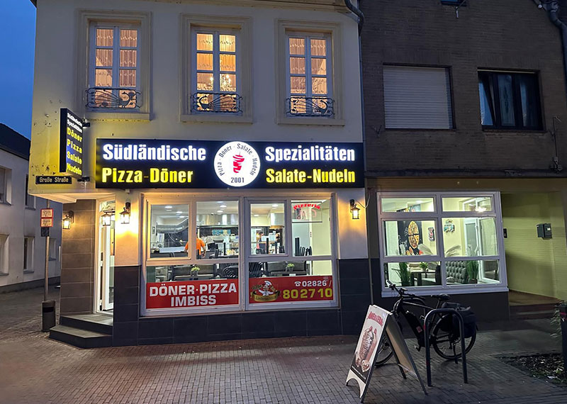 Außenansicht Südländische Spezialitäten Kranenburg in der Dunkelheit mit beleuchtetem Reklameschild