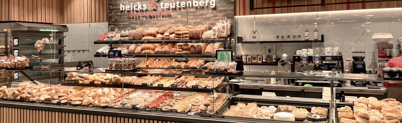 Moderne Theke der Bäckerei und Konditorei heicks & teutenberg liebe in backform mit großer Auslage an Backwaren und diversen Kuchen und Snacks