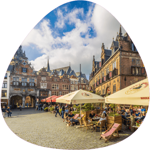 Marktplatz der niederländischen Stadt Nijmegen mit historischen Gebäuden und Gastronomie (Schirme, Liegestühle)