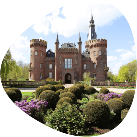 historisches Schloss Moyland bei schönem Wetter mit Beet im Vordergrund