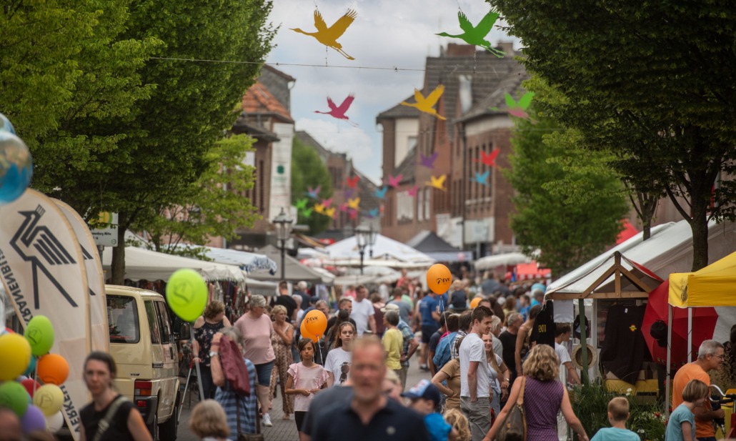 Große Straße mit Marktständen auf dem Stüppkesmarkt mit vielen Menschen und bunten Kranichen (Foto: Markus van Offern/Gemeinde Kranenburg)